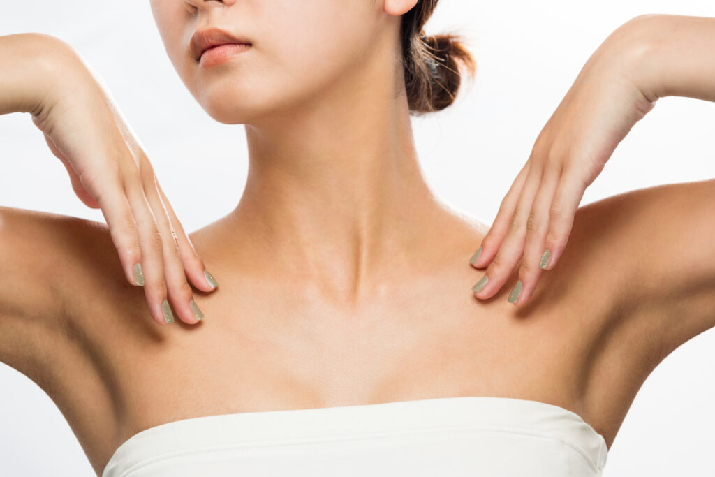 In foto, una donna raffigurata dal mento fino al decolleté che indica il suo collo. Significa che oltre alla cura del viso, applica i prodotti anche sul collo e décolleté
