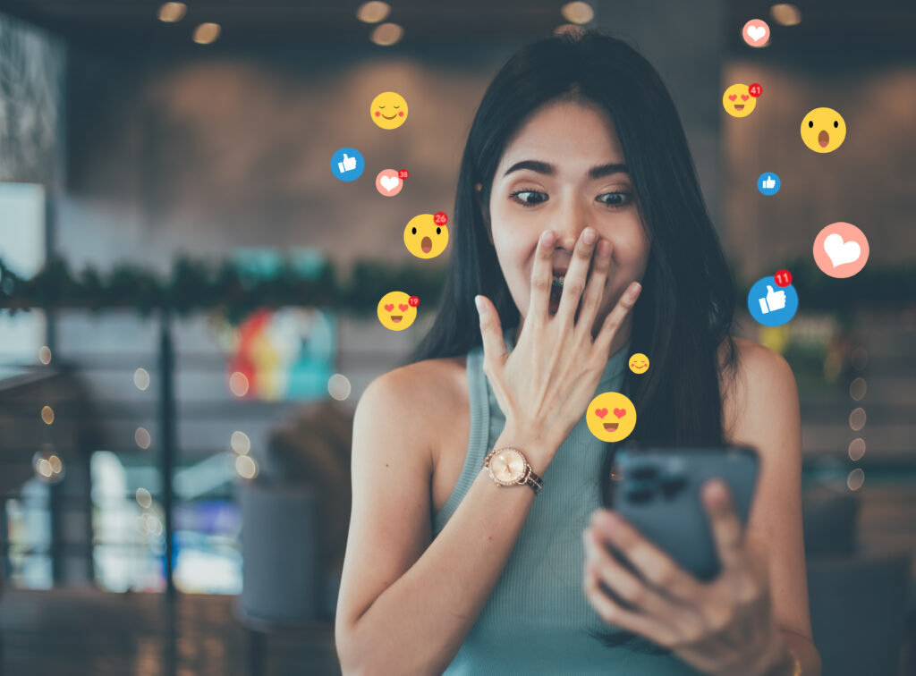 Una bellissima blogger, donna d'affari, vlogger o influencer riceve reazioni emoji ed emoticon sul suo dispositivo mobile durante la pubblicazione. Condivisione o registrazione di video sui social media e marketing del beauty