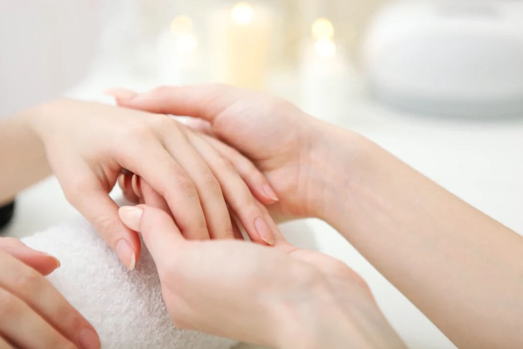 delle mani di una professionista che toccando delle mani di una cliente per eseguire un trattamento: rappresenta la salute e bellezza delle unghie
