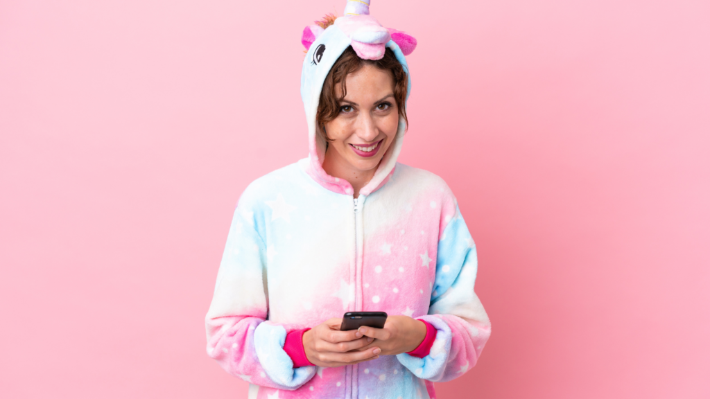 una donna su sfondo rosa con un pigiama e uno smartphone in mano: rappresenta il pigiama party educational