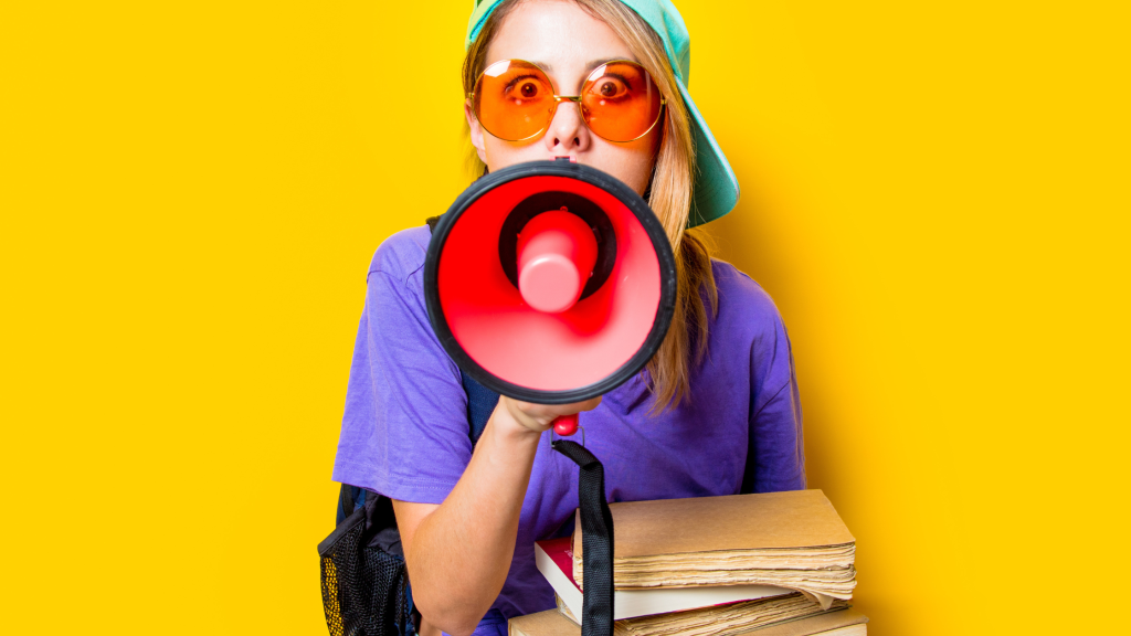 in foto una ragazza giovane con dei libri in mano e un megafono: rappresenta il tema dell'articolo, l'apertura delle votazioni del CISEP 2025.