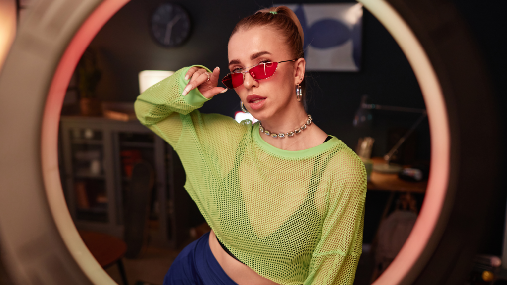in foto, una donna vestita di verde con degli occhiali di tendenza. rappresenta il tema dell'articolo, le tendenze beauty 2025.