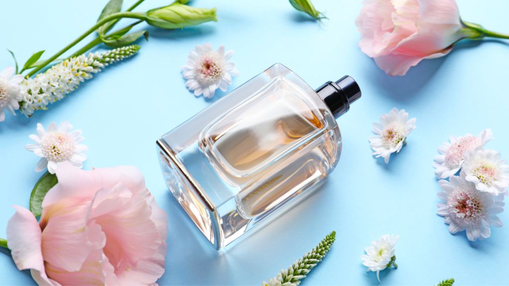 in foto una boccetta di profumo contornata da fiori: rappresenta il tema dell'articolo, i profumi.