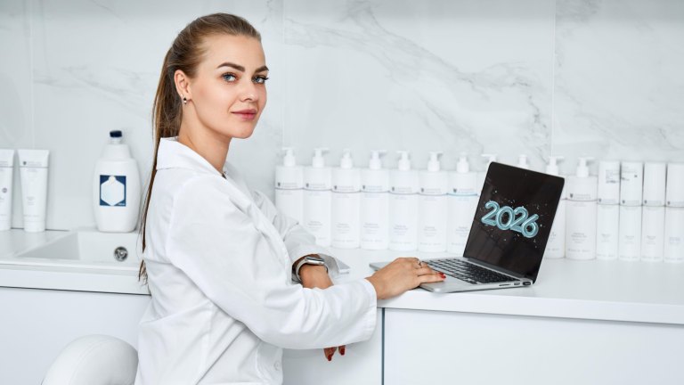 Estetista professionista in ambiente professionale e moderno, utilizza un laptop con la scritta 2026, circondata da prodotti skincare professionali: immagine simbolo della nuova estetica professionale orientata a competenza, tecnologia e visione futura.