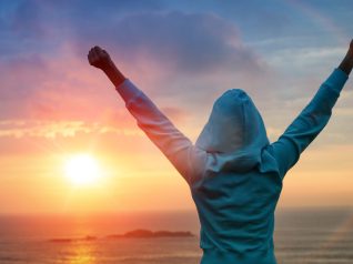 Risultati nello sport e nella vita e concetto di successo. Ragazza sportiva con vista posteriore che alza le braccia verso il bellissimo sole splendente.