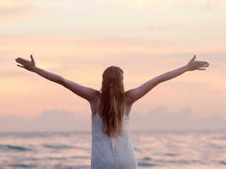 Una donna con le braccia aperte di fronte al mare al tramonto, simbolo di libert&agrave; e visione strategica. Proprio come nel marketing, una strategia ben definita permette di abbracciare nuove opportunit&agrave; con chiarezza e determinazione, trasformando ogni azione in un passo verso il successo.