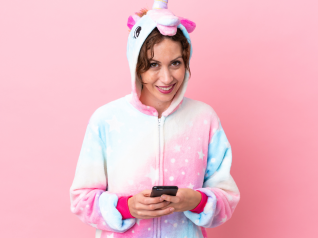 una donna su sfondo rosa con un pigiama e uno smartphone in mano: rappresenta il pigiama party educational