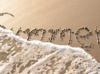 in foto la scritta summer sulla sabbia che viene candellata da un'onda del mare. rappresenta la fine dell'estate e la necessità si una skincare post estate.
